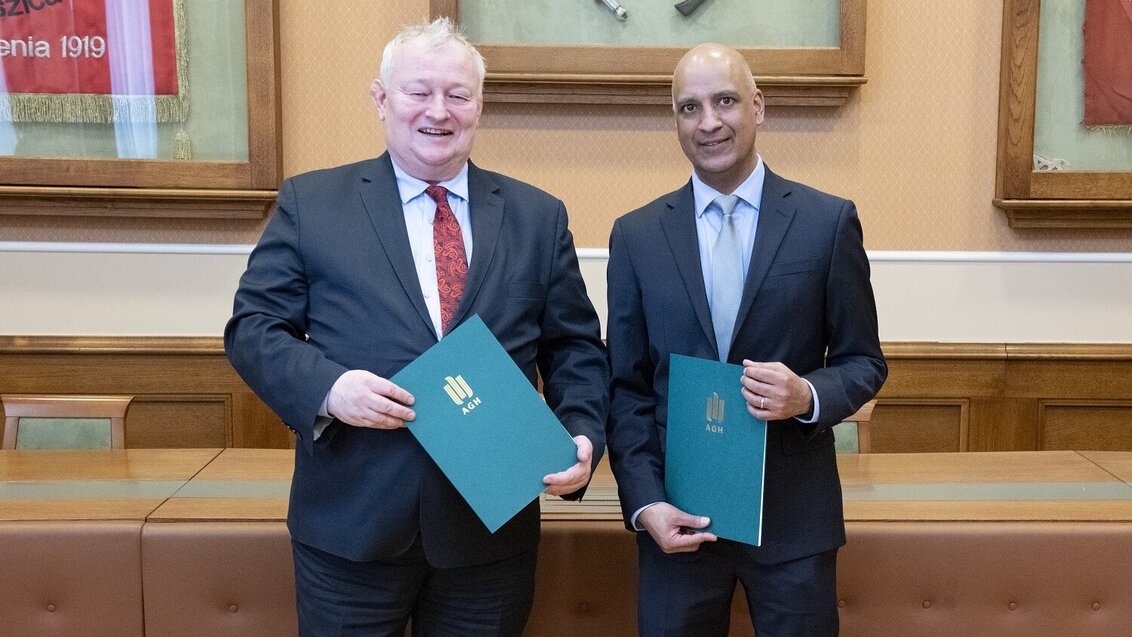 Na zdjęciu sygnatariusze umowy - stoją uśmiechnięci obok siebie, trzymając w dłoniach zielone teczki z dokumentami. Zdjęcie wykonane 