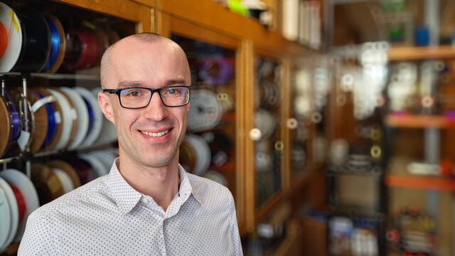 Zdjęcie prof. Kijanki (uśmiechnięty, młody mężczyzna z ogoloną głową noszący okulary ubrany w białą koszulę w ciemne kropki).