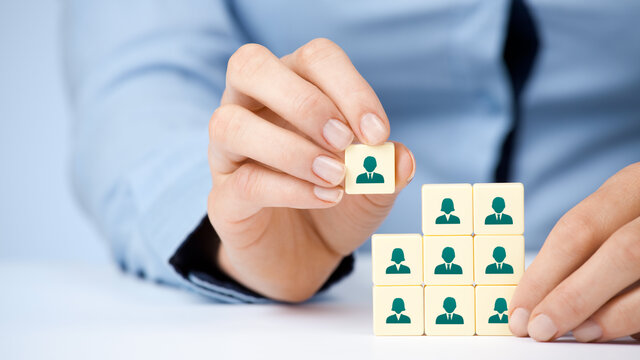 image of a hand holding a piece of a cube with icons of employees