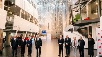 Image of two groups of people standing in a hall of a modern building, one of the people being the President of Poland