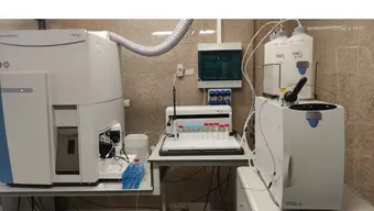 The photo shows an ion chromatograph connected to a mass spectrometer. Both devices are located on work benches next to test tubes and appropriately labelled reagents – for example, NHO3 visible on the right.