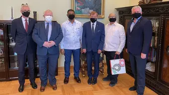 Gabinet Rektora AGH. Sześciu mężczyzn stoi obok siebie w rzędzie. Ich twarze i nosy zasłaniają maseczki. 