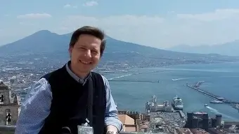 The photo shows a man with the panorama of Naples behind his back; Vesuvius volcano is in the background; on the right there is a gulf and the sea.