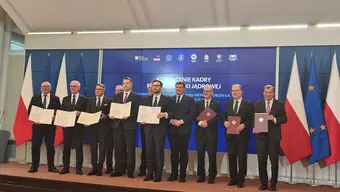 The photo shows the signers of the letter of intent, a group of people in a row holding copies of the document, presenting them to the camera.