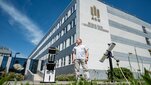 Dr Paweł Janowski standing in front of the buidling of the Faculty of Physics and Applied Computer Science in between two telescopes.