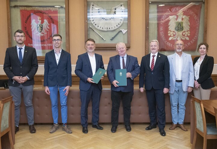A group of people in elegant attire standing in a room with traditional banners hanging on a wall