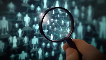 Grafika dekoracyjna: plansza z ikonkami sylwetek ludzi; nad nimi przyłożona lupa