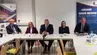 Pięć osób siedzi przy stole w sali konferencyjnej.