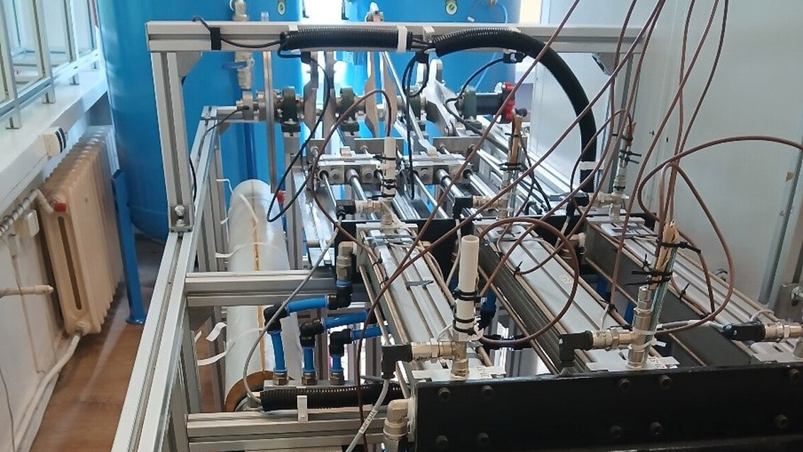 Industrial laboratory apparatus with metal tubing, valves, and sensors mounted on a test rig.