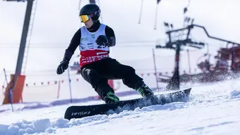 Zdjęcie snowboardzisty w trakcie zjazdu na stoku.