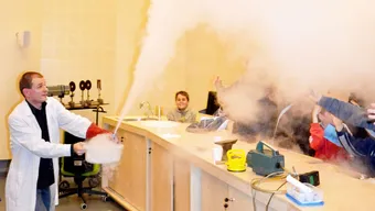 Naukowiec podczas pokazu z ciekłym azotem w auli, w której publiką są dzieci