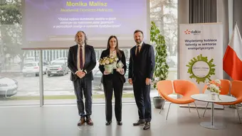 Photo of the AGH University graduate holding flowers with two representatives of Dalkia Polska
