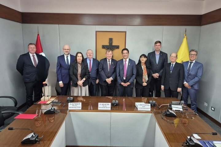 A group of people posing for a photograph standing behind a conference table.