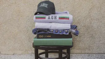 Zdjęcie kilku produktów ze Sklepu AGH ułożonych jeden na drugim na krześle