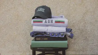 A stack of clothes, books, and a cap on a stool.