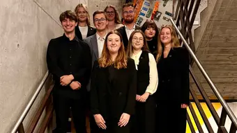 A group photo of young students on a modern staircase.
