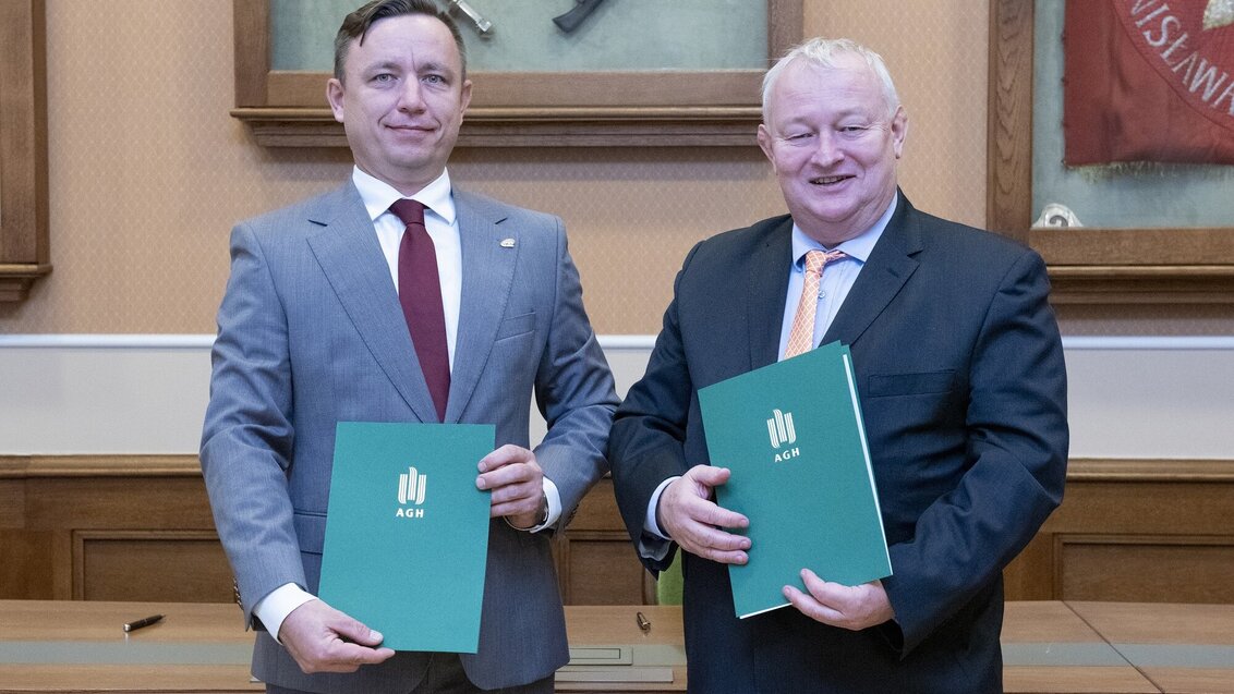 Photo of two smiling men in suits holding folders