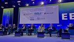 Sesja kongresowa. Osoby biorące udział w dyskusji siedzą obok siebie w fotelach. Jedna z nich trzyma w dłoni mikrofon.
