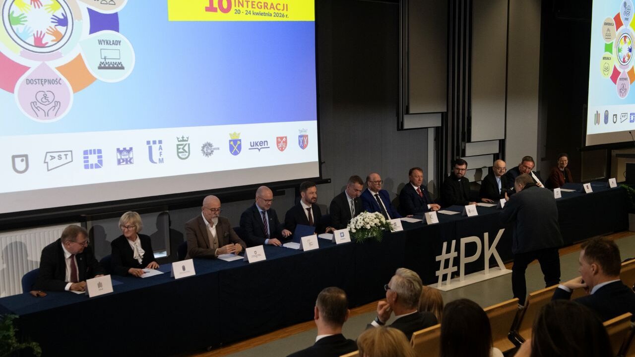 A group of people sitting behind a long table in conference setting with a projector screen behind them.
