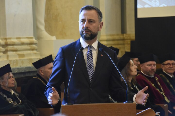 The Deputy Prime Minister speaking at a lectern. In the background, university officials in academic gowns