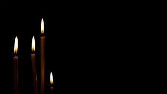 A black background with four slim candles on the left side