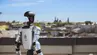 A humanoid robot with the ‘AGH’ logo stands outside the building. In the background, a monument and part of the façade featuring a column.