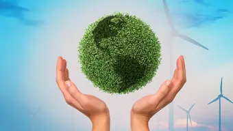 Abstrakcyjna grafika prezentująca kulę ziemską porośnietą roślinnością. Ziemia obejmowana jest przez dłonie. W tle krajobraz z turbinami wiatrowymi.