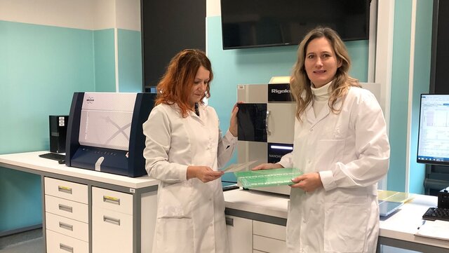 Image of two female scientists in labcoats standing in a lab
