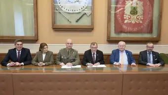 Przedstawiciele AGH oraz AWL siedzą przy długim stole konferencyjnym, podpisując dokumenty.