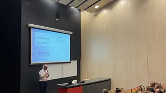 Image of the EARMA speaker during a presentation, meeting participants visible inthe audience