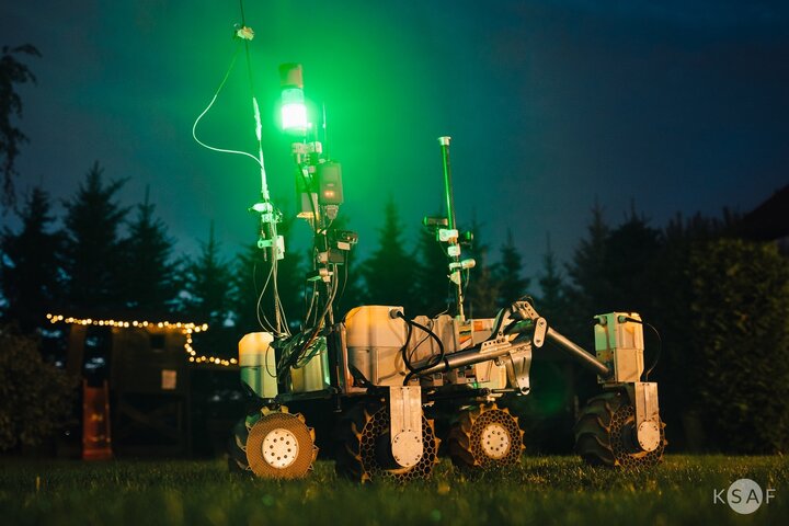 Kalman with research equipment. The photo was taken outside in the twilight, the area is illuminated by a lamp mounted on the robot, which emits bright green light.