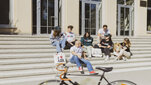 Students showcasing AGH University apparel and accessories on steps outside a university building.