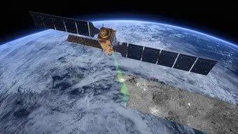 Grafika przedstawia satelitę, który przelatuje na orbicie Ziemi. Poruszający się satelita emituje w kierunku błękitnego globu falę radarową, oznaczoną symbolicznie kolorem zielonym. Fala pozostawia za sobą po prawej stronie radarowy obraz powierzchni terenu, który oznaczony jest symbolicznie na widocznym fragmencie kuli ziemskiej.
