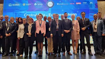 A group photograph of people dressed in business attire with conference badges on lanyards.