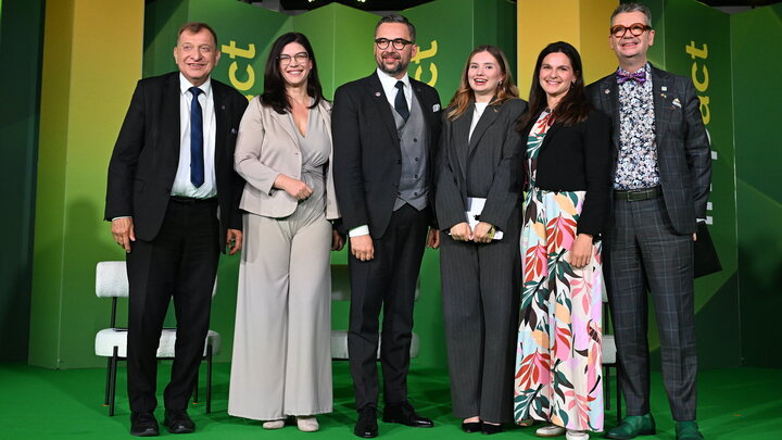 Six people in formal attire posing for a photograph standing close together.