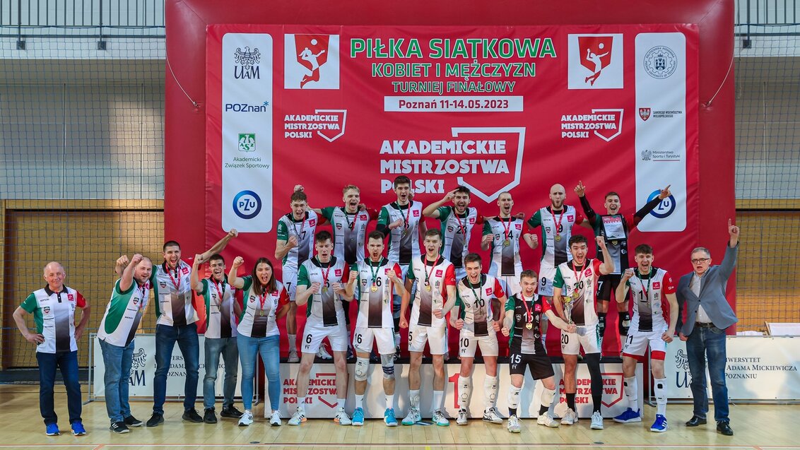 A group of AGH University players and their trainers. The contestants have gold medals hanging from their necks. They are wearing sports clothes in university colours. Their faces express joy and pride for the victory.