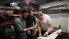 Three young men working on an unmanned aircraft in a workshop setting.