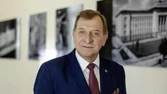 Image of a man standing in front of a wall with black and white images