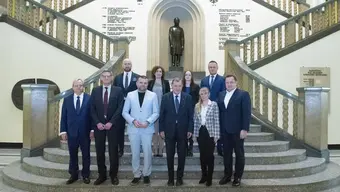 Grupowe zdjęcie osób uczestniczących w spotkaniu, wykonane na schodach w reprezentacyjnym holu budynku głównego AGH.