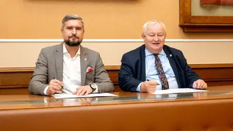 Dwóch mężczyzn siedzących przy stole w sali konferencyjnej