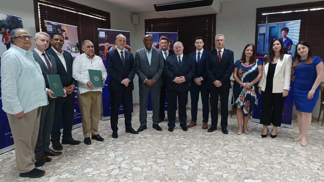 The photo shows the delegation at the Dominican Ministry of Energy and Mines. A group of elegantly dressed people in a semicircle posing for a photo.