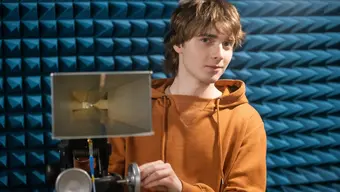 Image of a male student holding a specilist devise in a soundproofed room