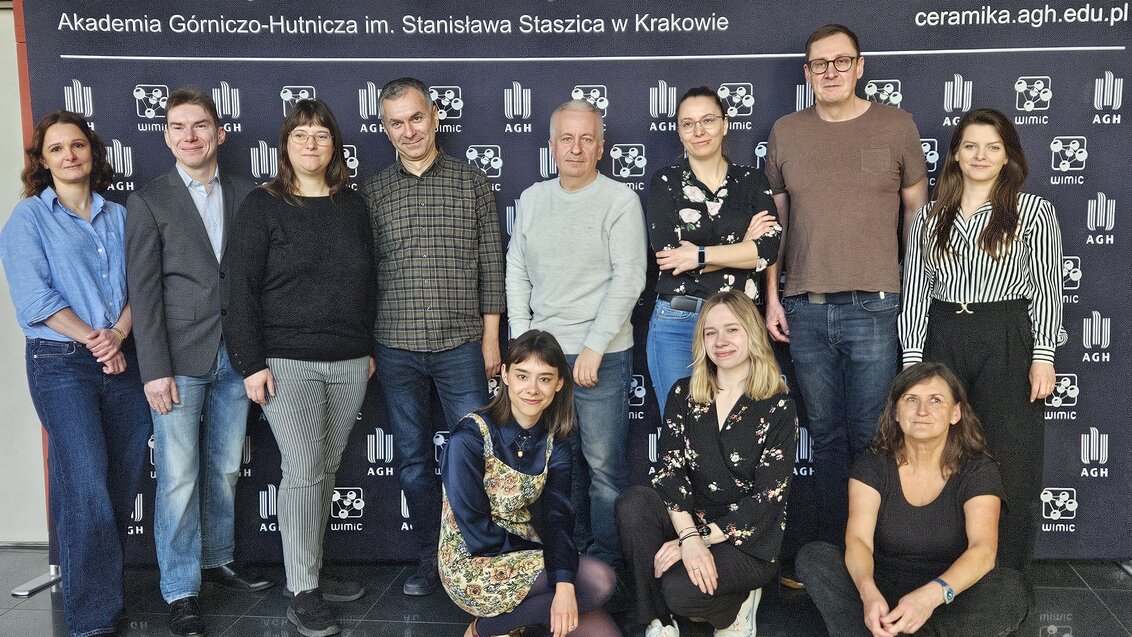 A group photograph of people in casual attire in front of a faculty backdrop.