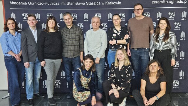 A group photograph of people in casual attire in front of a faculty backdrop.