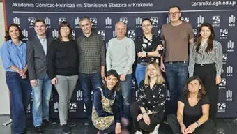 A group photograph of people in casual attire in front of a faculty backdrop.