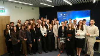 A large group of young people standing in a room in front of a backdrop with POLSA branding.
