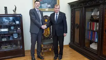 Na zdjęciu konsul i rektor stoją obok siebie, podając sobie dłonie. Zdjęcie wykonane w gabinecie rektorskim.