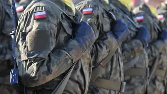 Na zdjęciu widoczny fragment ustawionych w szeregi umundurowanych żołnierzy. na ramionach maja naszywki z flagą Polski.