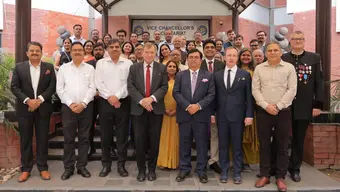 A group photo in Indian university setting with people in business attire.