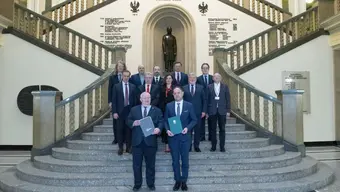 An image of a group of people in business attire on a decorative staircase in the main building of AGH University.
